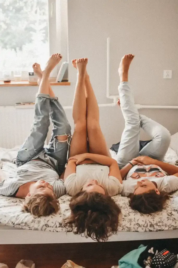 three people in an enm relationship lying on bed with feet in the air